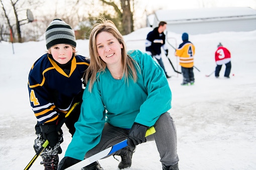 Ice Hockey Mom with son on outdoor pond