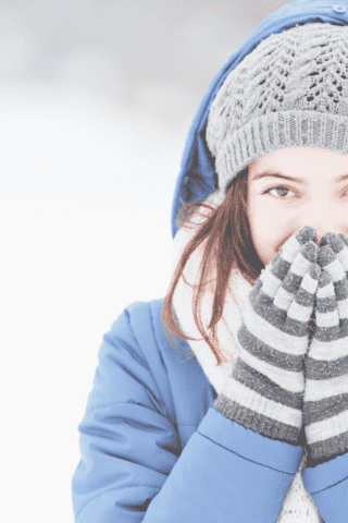 Hockey Mom in winter clothes covering her mouth and warming her fingers