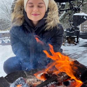 Woman in back of fire pit next to outdoor ice hockey rink 