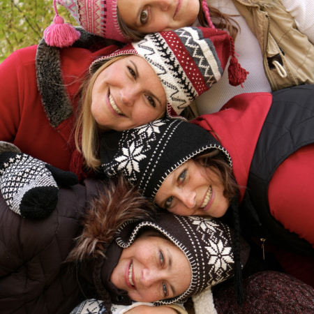 Four Moms with winter hats pose togerther