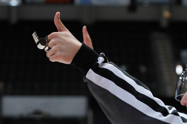 Referee calling an Embellishment penalty with arms up and whistle in hand