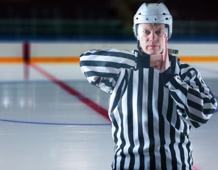 Picture of a Ice Hockey Referee calling a Boarding Penalty with one hand in a fist and other hand straight up 