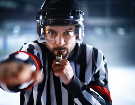 Ice Hockey Referee with whistle calling a penalty