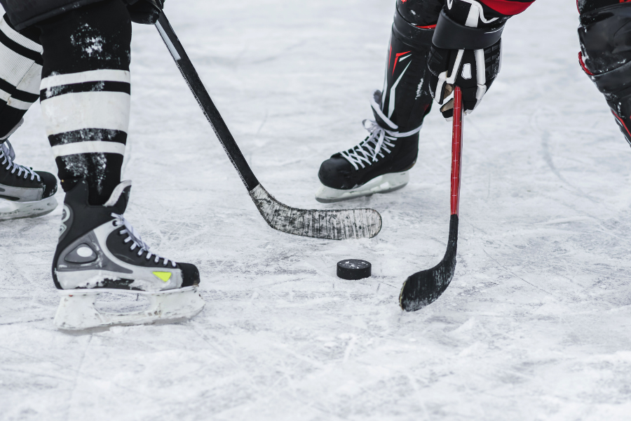 Two players at a face off, sticks, skates and a puck