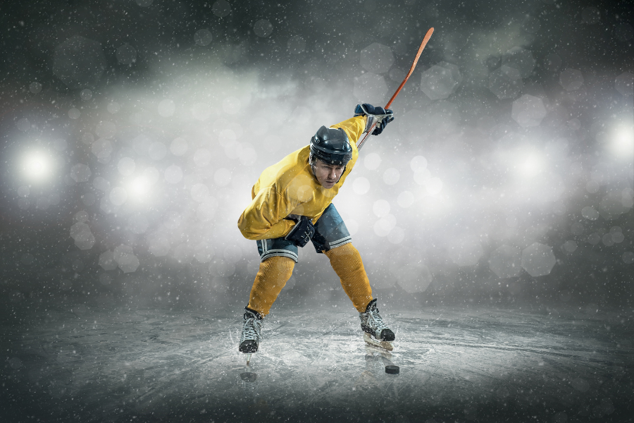 hockey player in yellow jersey taking successful slap shot