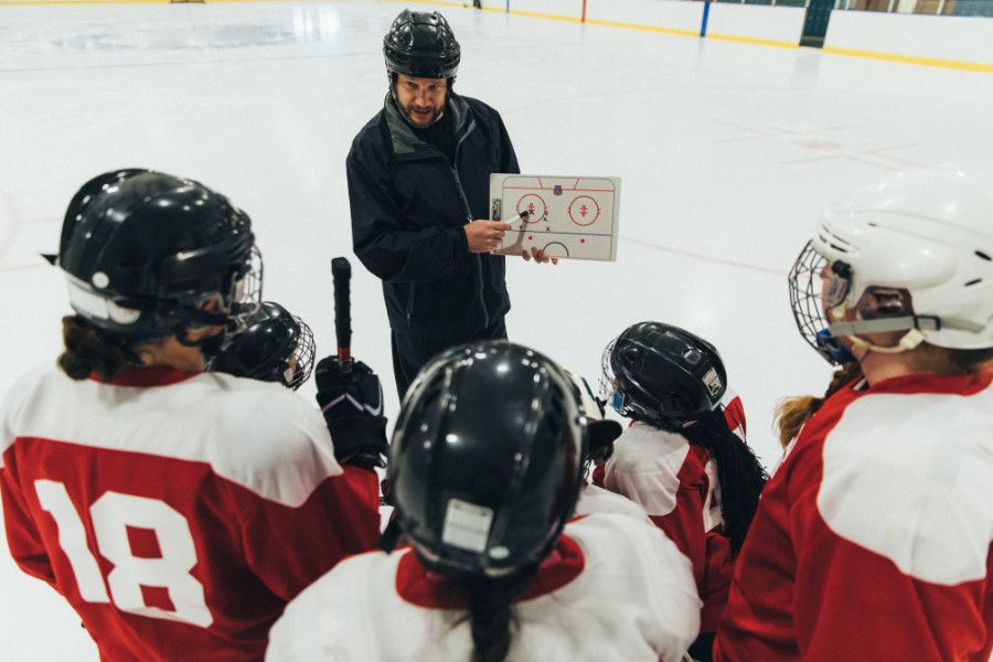 coach describing a play on white board to ice hockey team 