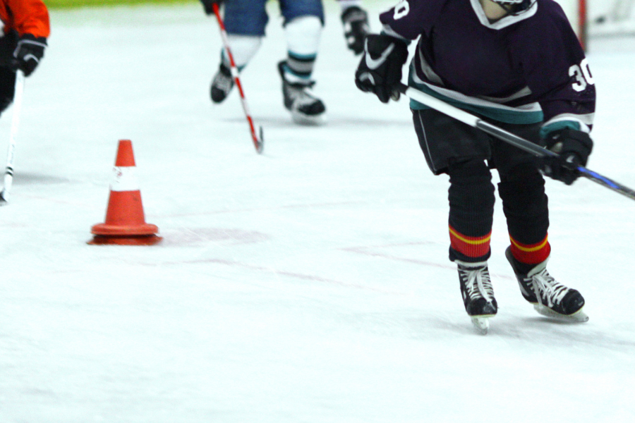 child ice hockey playe practicing skating skills 